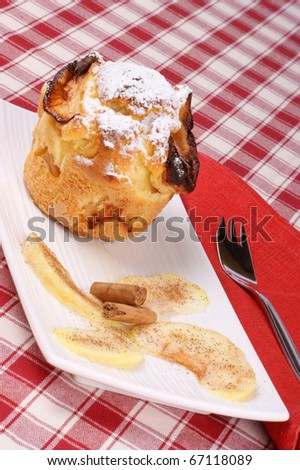 Apple muffin served on a white plate with candied apple slices and cinnamon