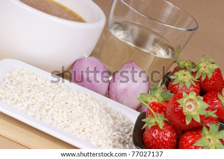 Ingredients for risotto with strawberries: white rice, strawberries, onion, white wine and vegetable stock. Studio shot over light brown background. Selective focus, shallow DOF