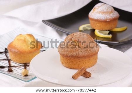 Cinnamon muffin on a cake stand and assorted muffins out of focus in the background. Selective focus, shallow DOF