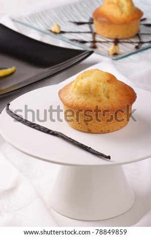 Vanilla muffin on a cake stand and assorted muffins out of focus in the background. Selective focus, shallow DOF