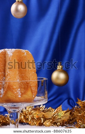 Christmas composition against a bright blue background: Pandoro, a typical italian Christmas cake, on a glass cake stand and Christmas decorations