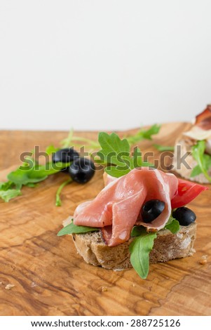 Mini party sandwich with ham, rocket, olives on the wood.