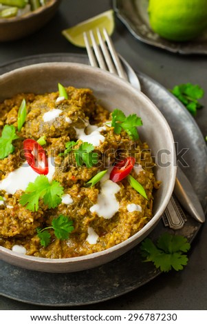 Indian beef curry with coriander and chili with limes on the side.