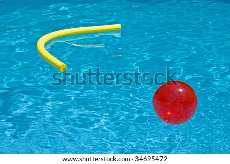 red ball and yellow foam noodle in the blue water of the pool