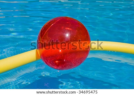 red ball and yellow foam noodle in the blue water of the pool