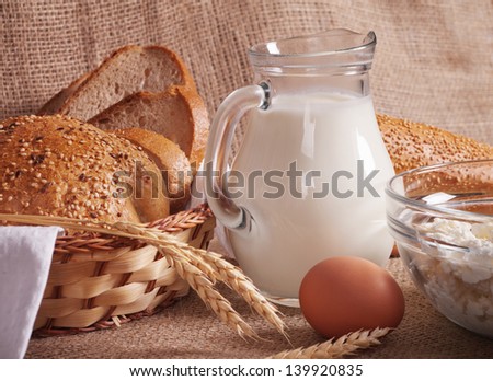jug with milk, eggs, cottage cheese and bread on burlap background
