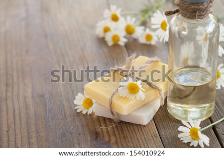 Bar of natural handmade soap and chamomile on wooden background. Selective focus.