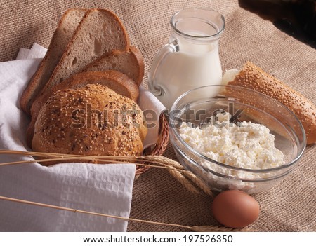 jug with milk, eggs, cottage cheese and bread on burlap background