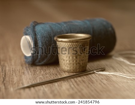 thimble and needles for sewing close-up on a background thread spools. macro