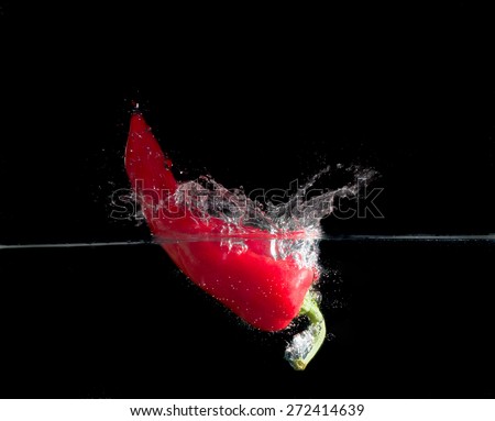 red paprika splash in water on black background.