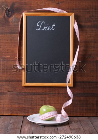 Black chalkboard for menu and apple over wooden background. Diet food concept.