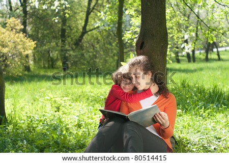 Mother and Daughter reading the Book in a park.Education concept