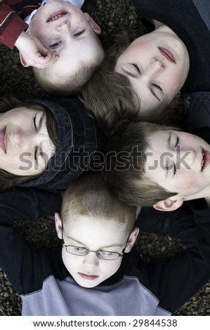 Five young boys with their heads together making a circle.All but one has their eyes closed.
