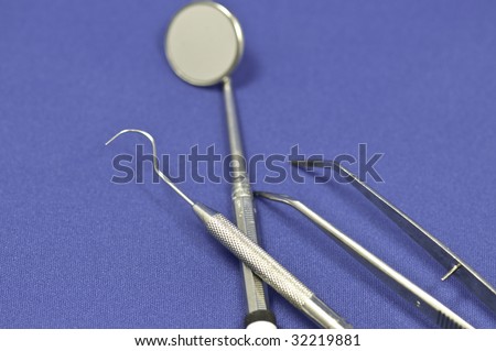 Three piece dental instrument on a blue background. The focus is on the center of the front pick.