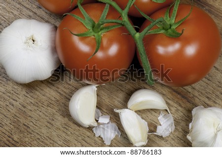 Top view of tomatoes and garlic on a wooden table top.
