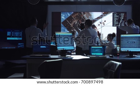 Group of supervisors celebrating docking of spaceship in dark room of mission control center. Elements of this image furnished by NASA.
