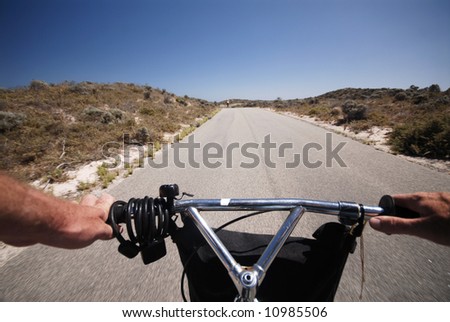 Cyclist view of riding bike down desert road