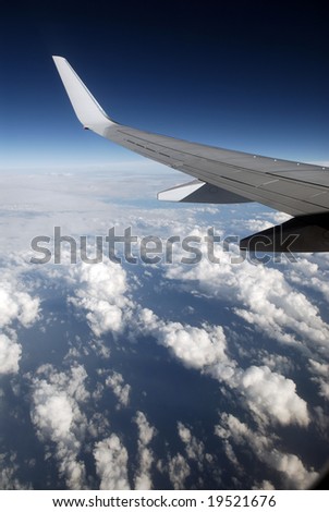 View of jet plane wing with cloud patterns and copy space