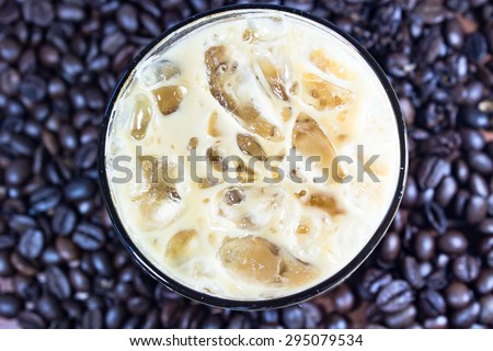 Ice coffee latte  with blur background and look from top feel full refresh with Black and brown coffee beans background  that is the beautiful aroma to wake up during working time.