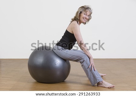female coach shows exercise using a pilates ball