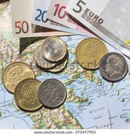 KETTERING, UK - JULY 1, 2015: Greek Euro exit concept of a Greek map with Euros and Drachma coins photographed with bright highlights and shadows for dramatic effect, photographed from above.