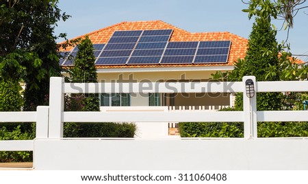 Solar panel on a orange roof reflecting the sun and the cloudless blue sky