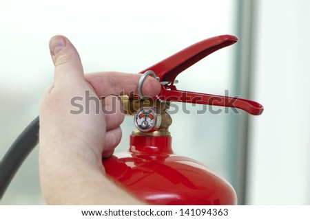 white hand pulls the pin from the extinguisher