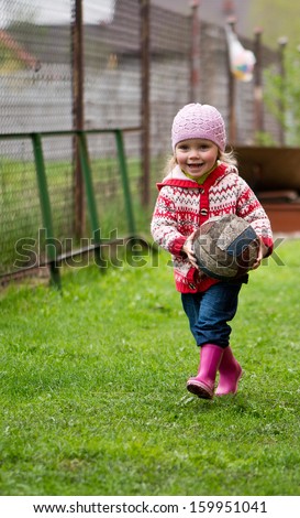 girl in rubber boots, runs with the old worn ball