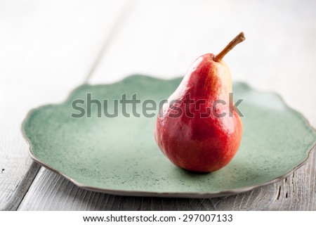 Ripe pear on the green plate on wooden table