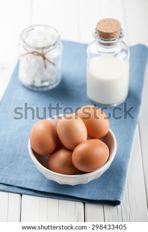 Eggs, milk and white sugar on wooden table