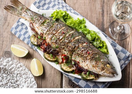 Baked fish with vegetables and a glass of white wine
