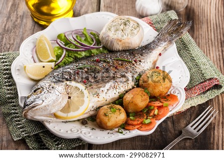 Baked fish dorado with vegetables on wooden table