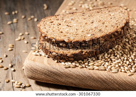 Sliced rye bread with seeds on a cutting board on wooden table