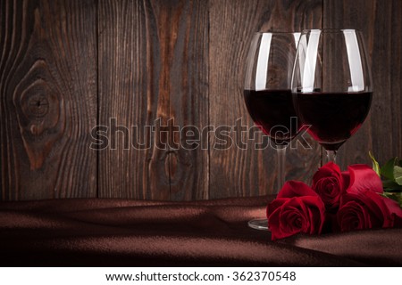 Two glasses of red wine and red roses on brown silk