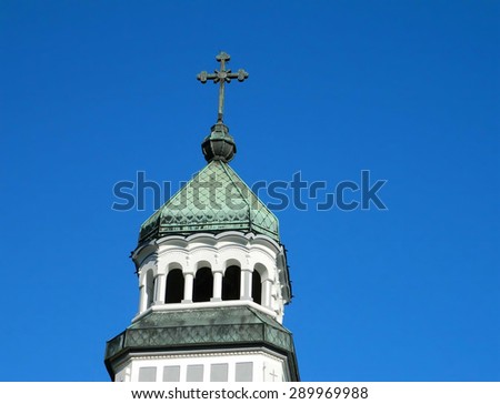 Orthodox church tower in Medias, Sibiu, Romania. White and green tower with cross on top, while sharing many traditions, East and West in Christianity began to diverge from each other.