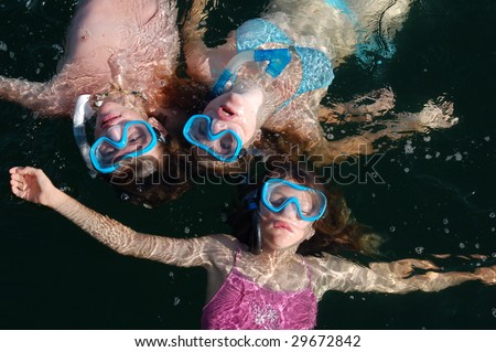 3 kids in swimming masks, floating on their backs