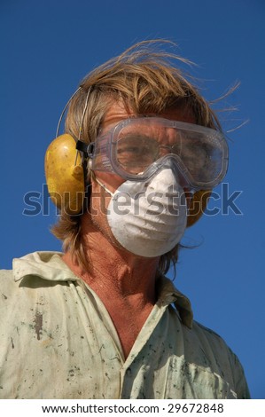 Man wearing industrial mask, eye protection, and ear defenders
