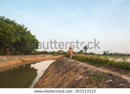 Namdinh, Vietnam - July 13, 2015: a woman come back home on a small dike