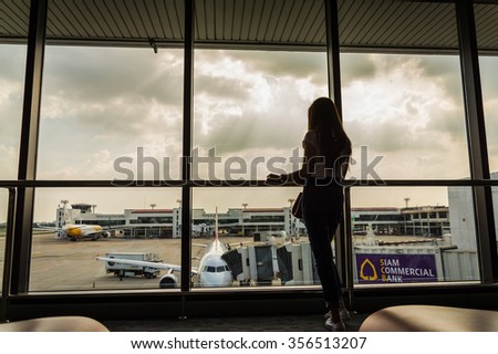 Girl at the airport window, Bangkok - August 6: Don Muang Airport on 3 November , 2015  at Don Muang Airport in Bangkok, Thailand.