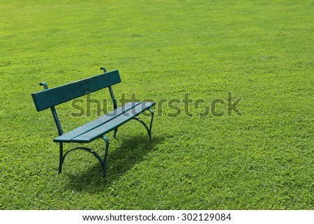 Lonely green wooden bench on short cut grass on sunny day