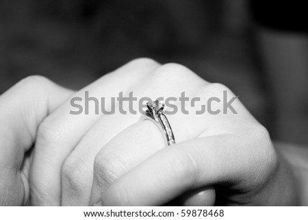 A diamond engagement ring on a lady\'s ring finger.