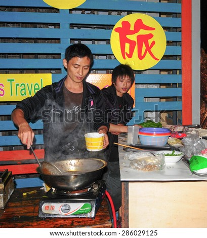 FENGHUANG - MARCH 23, 2015: Chinese men cooking traditional street foods in Fenghuang County. According to the Food and Agriculture Organization, 2.5 billion people eat street food every day.