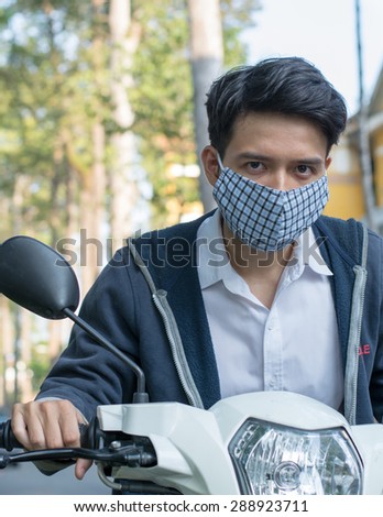 An Asian man wearing a mask to lessen the effect of toxic, traffic pollution in many Asia city..