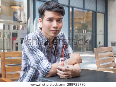 Asian young man holding a cup of coffee, sitting at the coffee shop in Saigon, Vietnam.