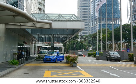 SINGAPORE - MARCH 27, 2015. Cars and people on the street in Singapore. There are more than 7,000 multinational corporations from US States, Japan and Europe in Singapore.