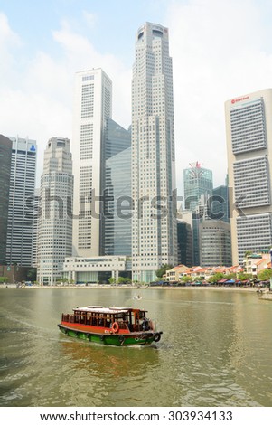 Singapore - June 1, 2015. A tourist boat floating on Singapore river with many buildings. Tourism also forms a large part of the economy, with over 15 million tourists visiting the city-state in 2014.
