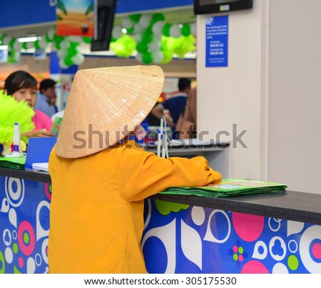 Saigon, Vietnam - Aug 1, 2015. An unidentified old woman with conical hat at Coopmart supermarket in Saigon, Vietnam.