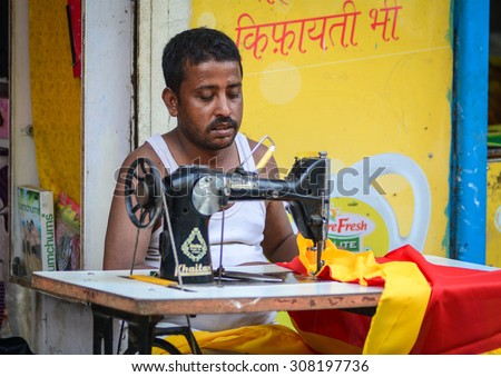 Gaya, India - Jul 22, 2015. Portrait of Indian man tailor at work place with sewing machine at the market in Bodhgaya, India.