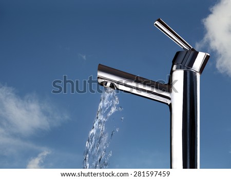 A kitchen faucet with running water is shown against a blue sky indicating clean, fresh, healthy water