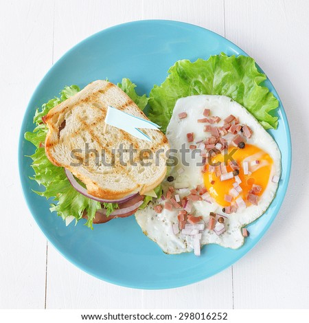 Sandwiches and fried eggs on a blue plate on a light background, view from top